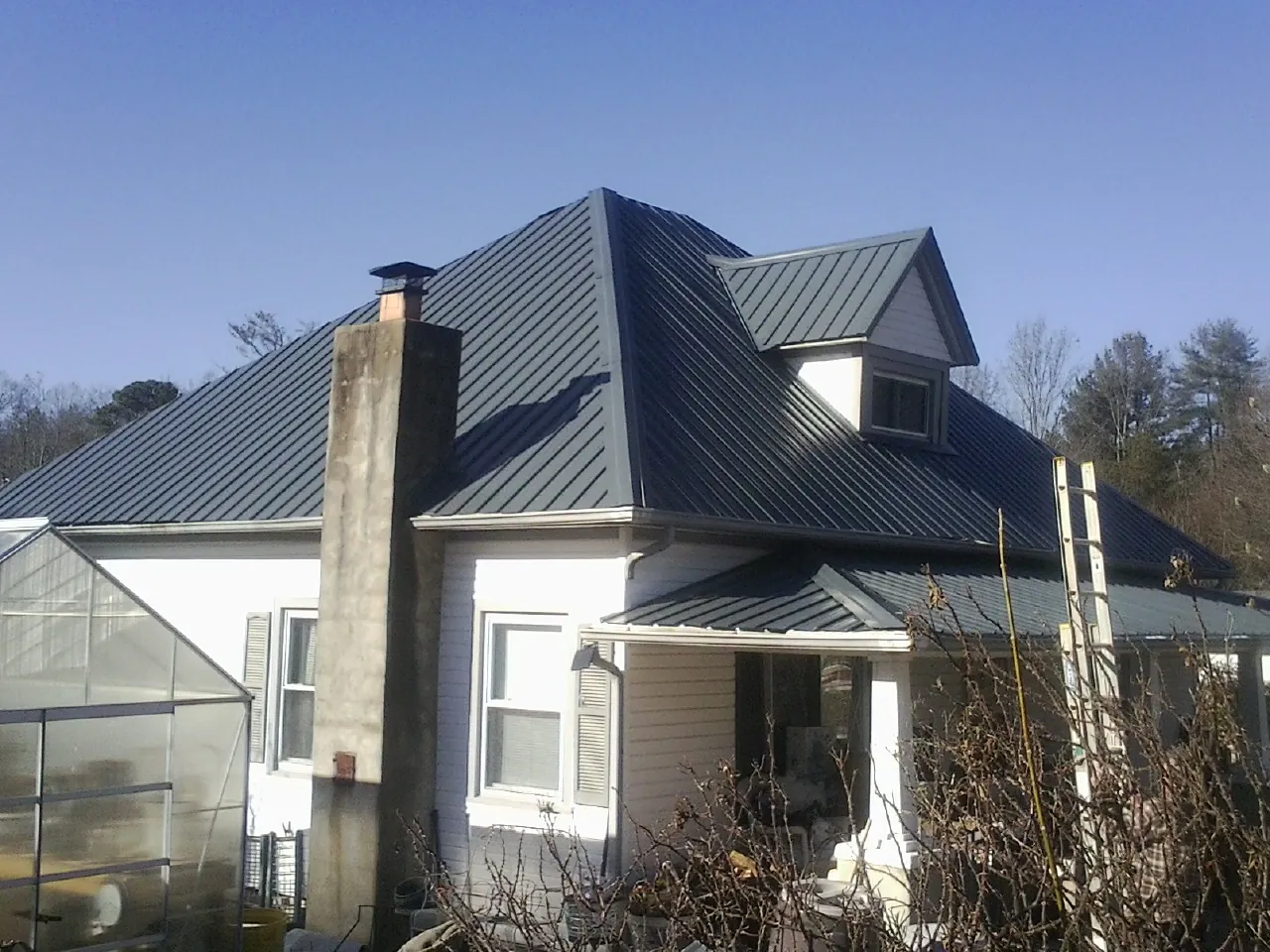 Dark blue standing seam metal roof on a white farmhouse with dormer — Slate & Tile Roof Repair by Roofing Brothers in Camilla