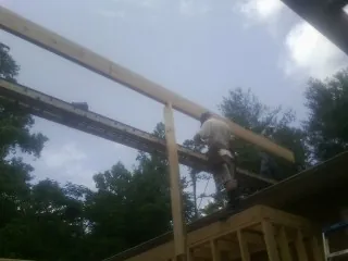 Carpenter setting a ridge beam over a new addition frame — Ice Dam Removal by Roofing Brothers in Camilla