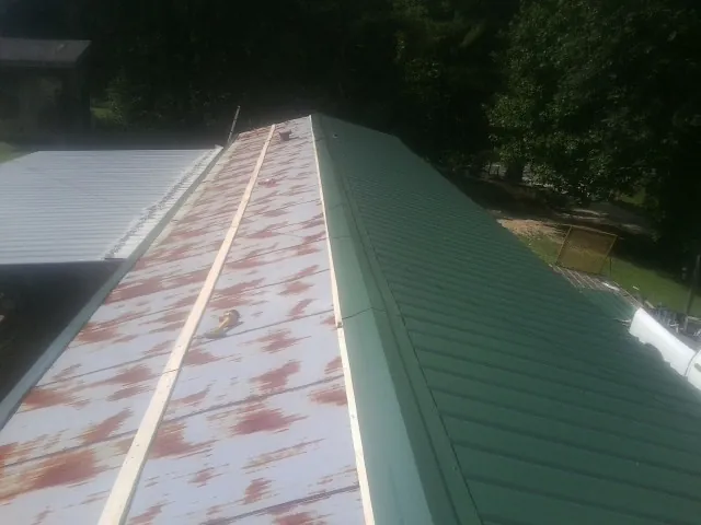 Old rusted panels beside newly installed green metal roofing — Wind Damage Roof Repair by Roofing Brothers in Camilla