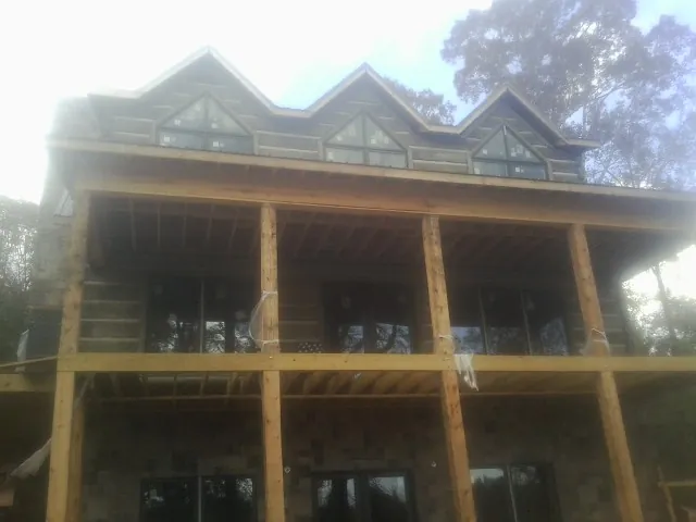 Dormers and porch framing on a large log home under construction — Roof Coating work by our crew in Camilla