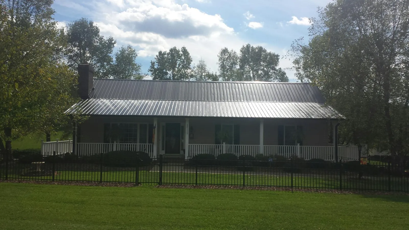 Gray metal roof on a brick ranch with a full width front porch — Gutter Guard Installation work by our crew in Camilla