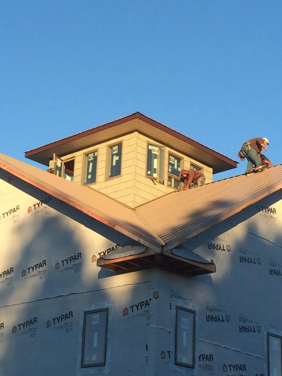 Roofers working around a rooftop cupola on a new metal roof at sunset — Roof Waterproofing in Camilla by Roofing Brothers